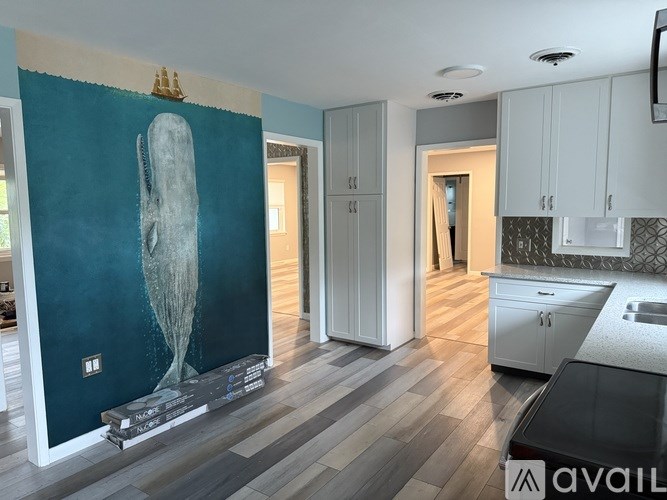 A kitchen with a large painting of a whale on the wall.
