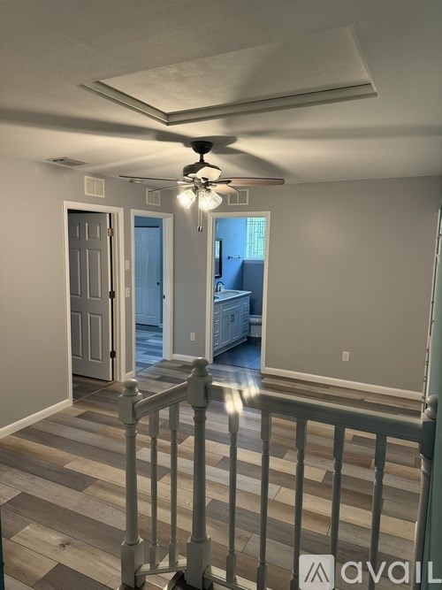 A room with a ceiling fan and a balcony with a railing.