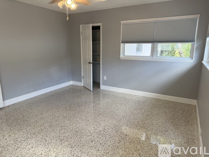 A room with a ceiling fan, a door, and a window with blinds.