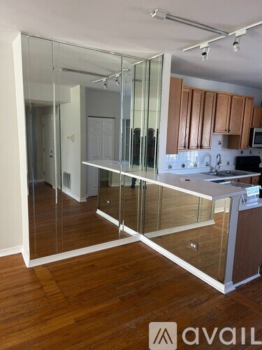A modern kitchen with wooden floors and a glass partition wall.