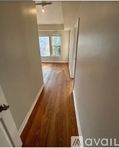 A hallway with wooden floors and white walls.