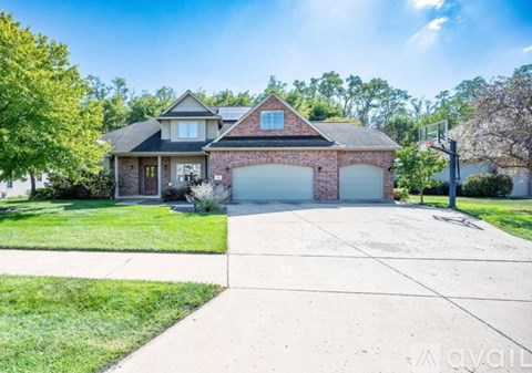 A two-story house with a garage is surrounded by a well-kept lawn.