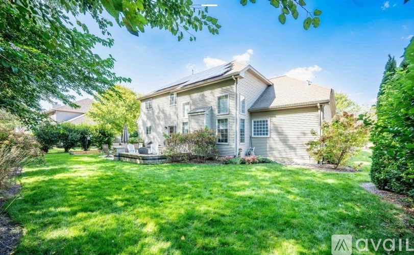 A house with a well-maintained lawn and trees in the background.