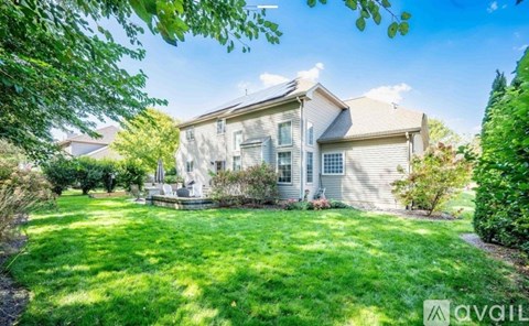 A house with a well-maintained lawn and trees in the background.