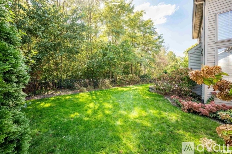 A well-maintained lawn with trees and a house in the background.