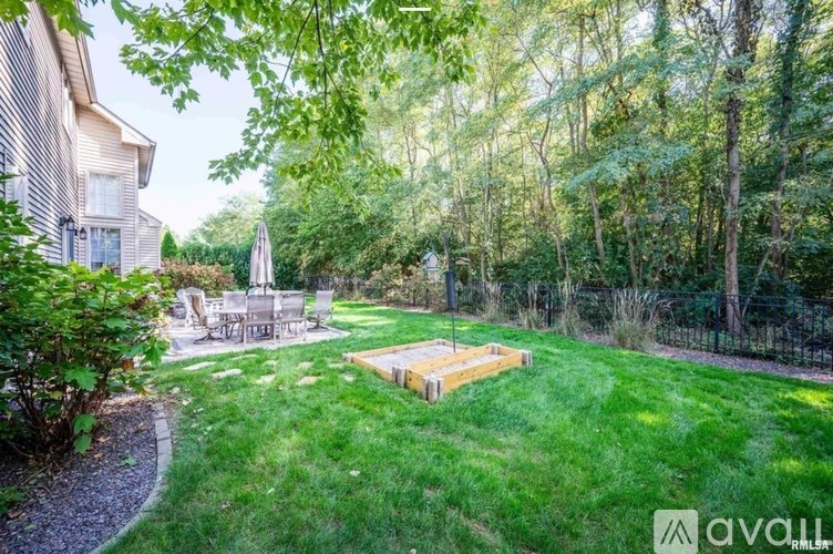 A backyard with a wooden deck and a white umbrella.