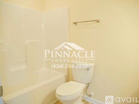 A white toilet in a bathroom with a Pinnacle Properties sign on the wall.