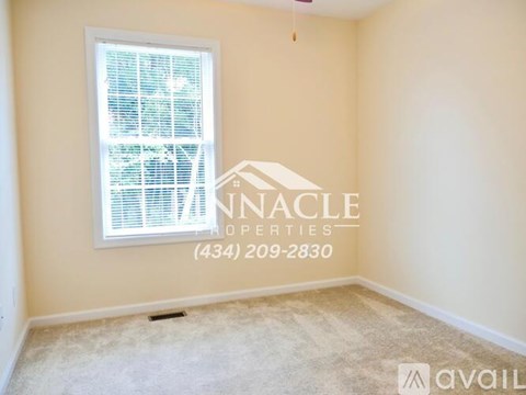 A room with a window and a carpeted floor is available for rent.