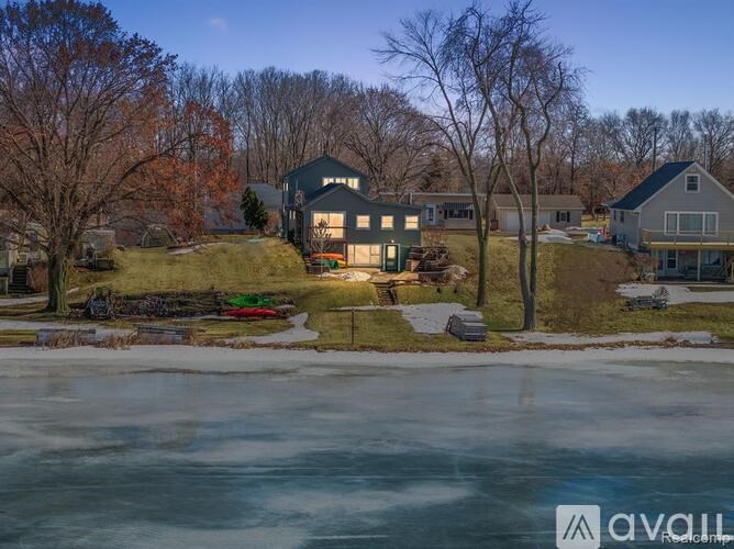 A house with a large front yard and a pond in the foreground.