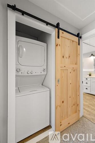 A white washing machine is installed in a wooden door cabinet.