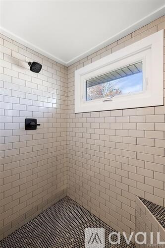 A bathroom with a window and a tiled wall.