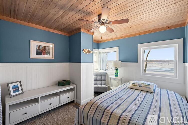 A bedroom with a bed, a bench, and a ceiling fan.