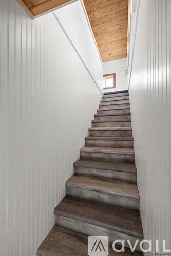 A set of stairs with wooden steps and white walls on either side.