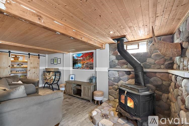 A wood stove is in a stone fireplace in a room with a couch.