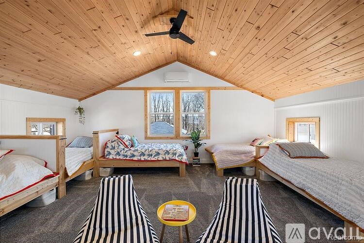 A room with wooden walls and ceiling, containing two beds and a table.