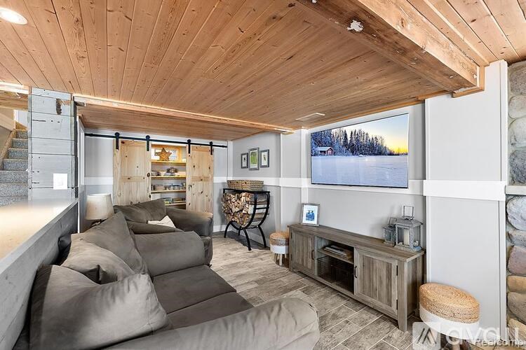 A living room with a grey couch and a wooden ceiling.
