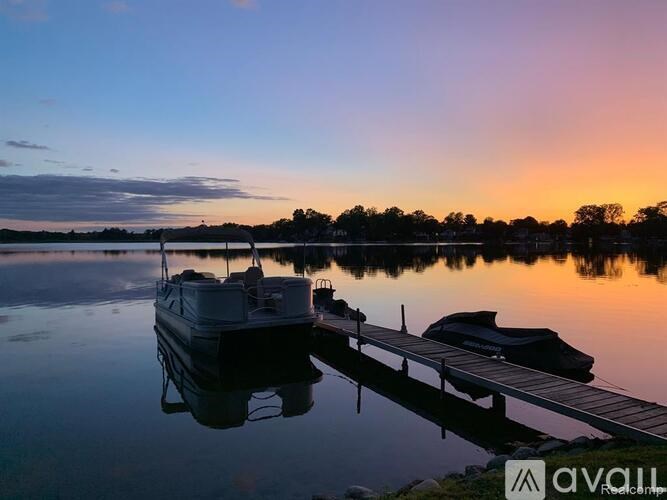 A boat is docked at a pier with a sunset in the background.