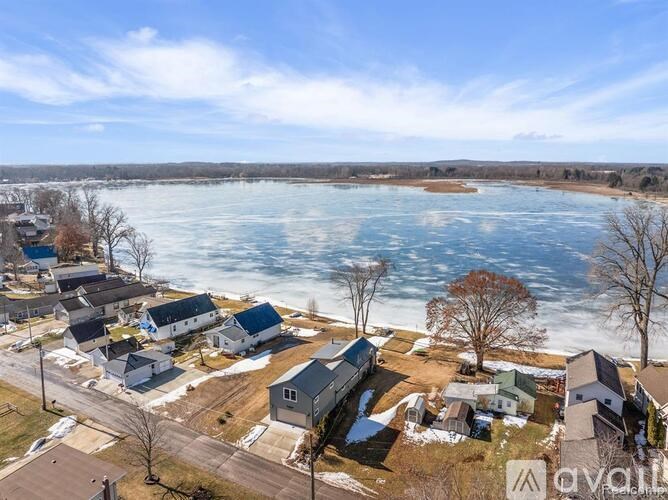 A bird's eye view of a residential area with houses and a frozen lake in the background.