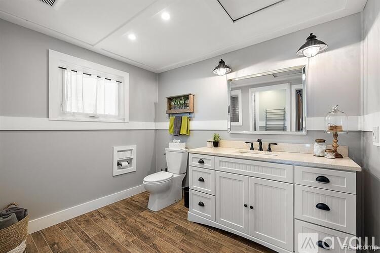 A bathroom with a toilet, sink, and mirror.