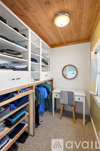 A small room with a desk and a large closet with clothes.
