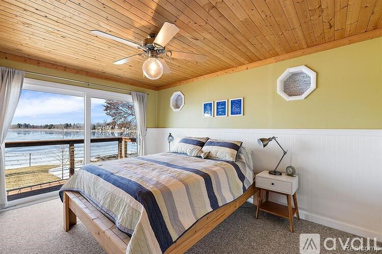 A bedroom with a bed, nightstand, and a window overlooking a body of water.