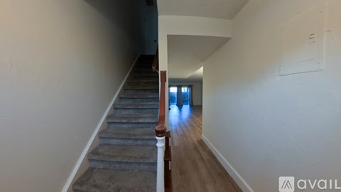 A hallway with a staircase leading to a door.