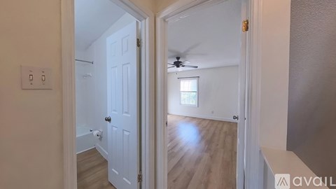 A white door is open to a room with a ceiling fan and a window.