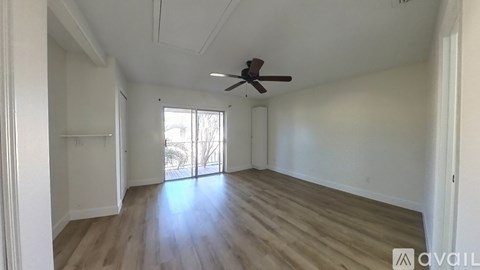 A room with wooden flooring and a ceiling fan.
