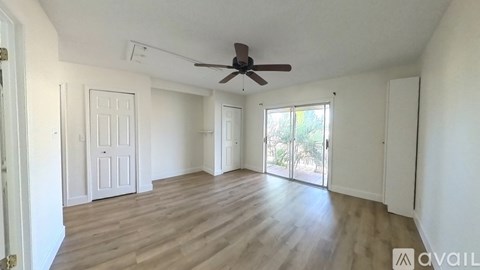 A spacious room with wooden flooring and a ceiling fan.