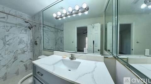 A bathroom with a marble countertop and a large mirror.