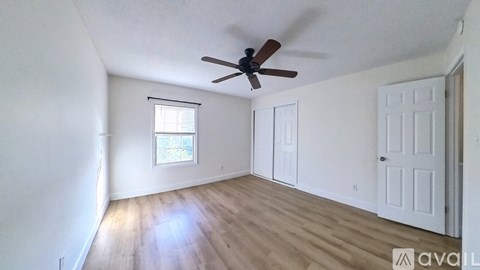 A room with a ceiling fan and wooden flooring.