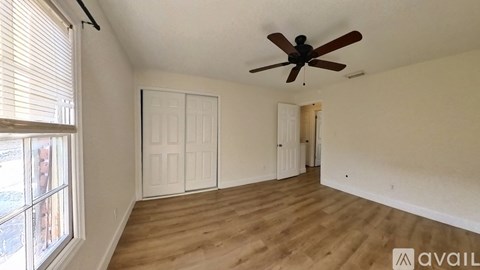 A room with a ceiling fan and wooden flooring.