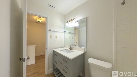 A bathroom with a white sink, a mirror, and a toilet.