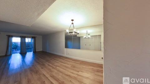 A room with wooden floors and a large window with curtains.