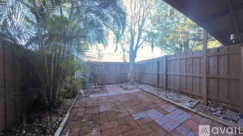 A backyard with a brick patio and a wooden fence.