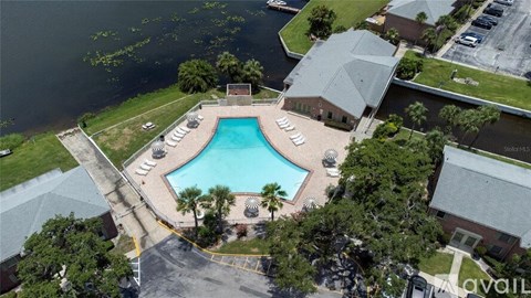 A bird's eye view of a swimming pool surrounded by buildings and trees.