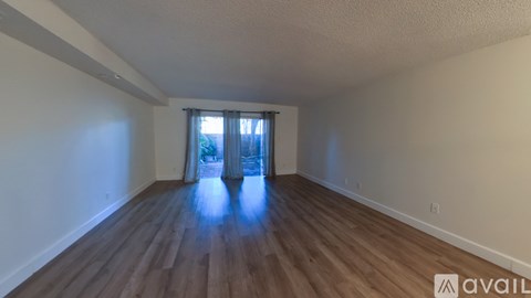 A room with wooden flooring and a window with curtains.