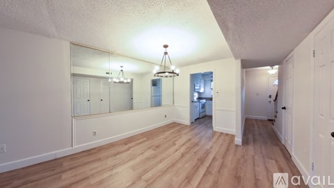 A spacious room with wooden floors and white walls.
