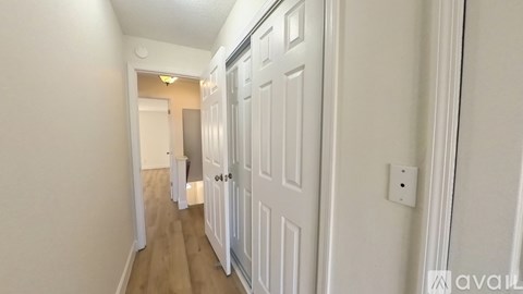 A long hallway with white doors and wooden floors.