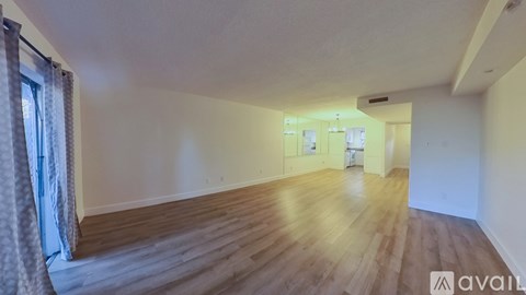 A spacious room with wooden flooring and a large mirror on the wall.