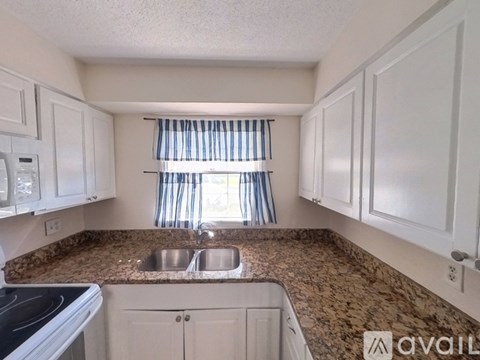 A kitchen with granite countertops and white cabinets.