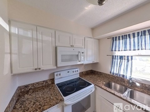 A kitchen with a granite countertop and white cabinets.