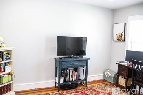 A black TV on a blue table with a rug in front of it.