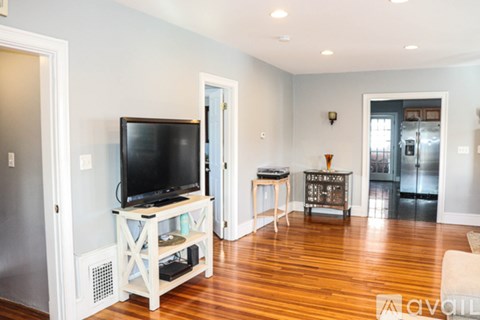 A living room with a television and a refrigerator.