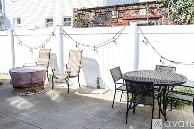 A patio with a table, chairs, and a hammock.