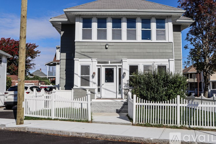 A grey house with a white picket fence in front.