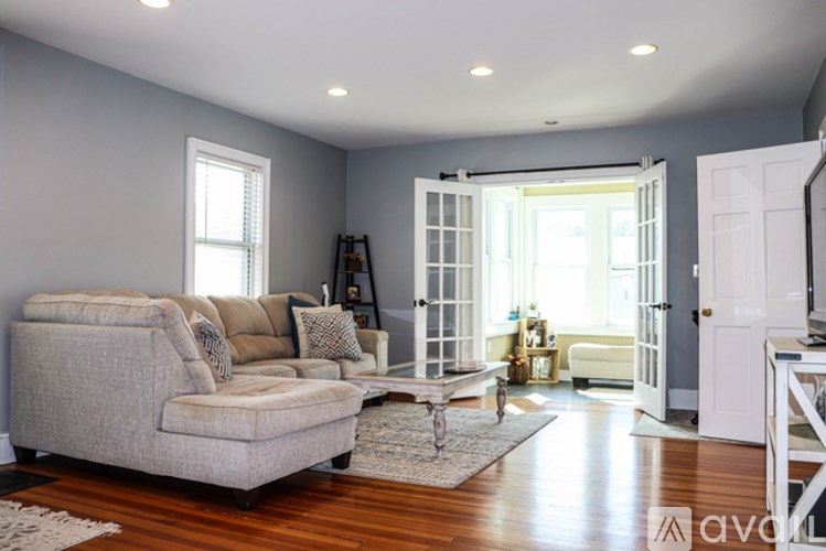 A living room with a grey couch and a wooden floor.