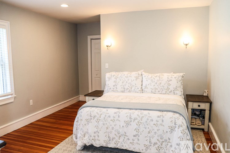 A bedroom with a bed, nightstand, and two wall sconces.