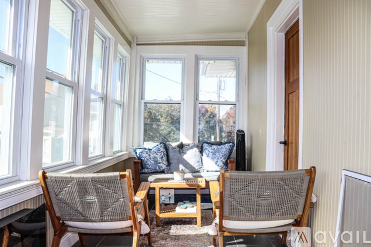 A sunny day in a room with a couch, two chairs and a table.