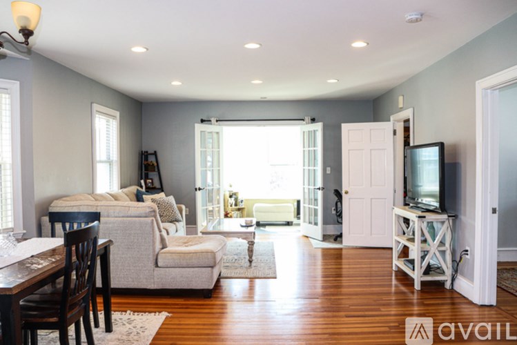 A living room with a couch, a chair, a television, and a window.